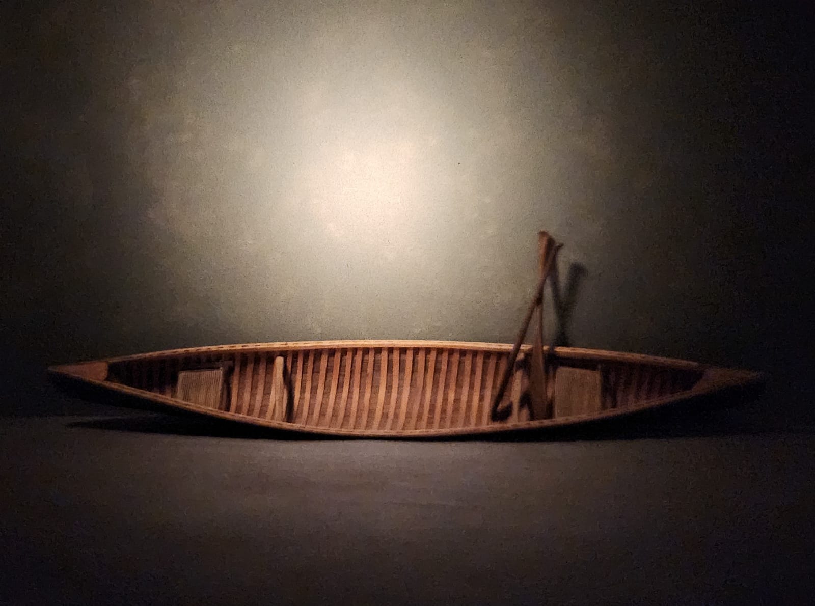 dagrosa-canoe-vessel-of-question “Thirty‑inch wooden canoe hanging on a wall, photographed with soft directional light.”